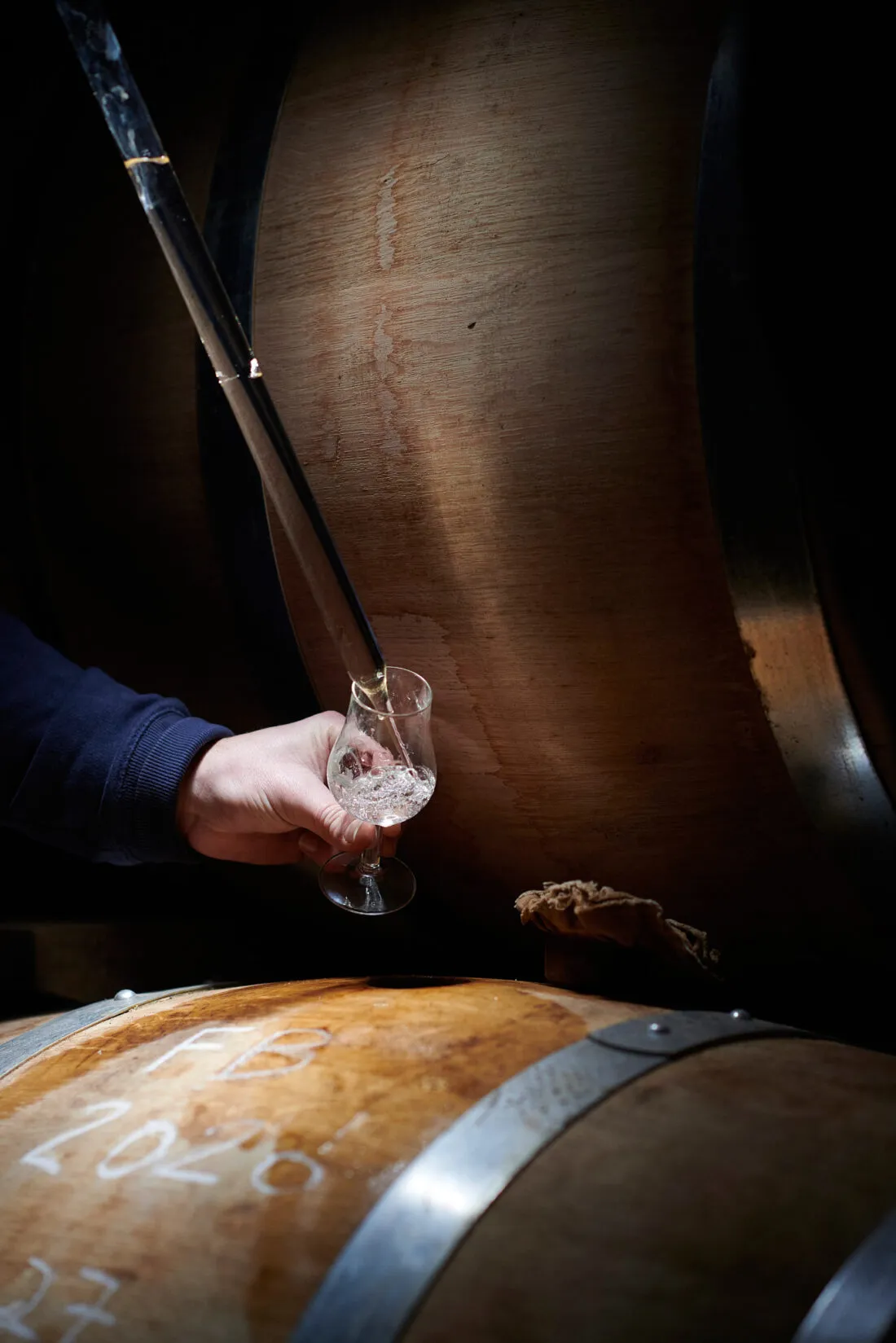 Prélèvement à la pipette dans une barrique de cognac, chai artisanal